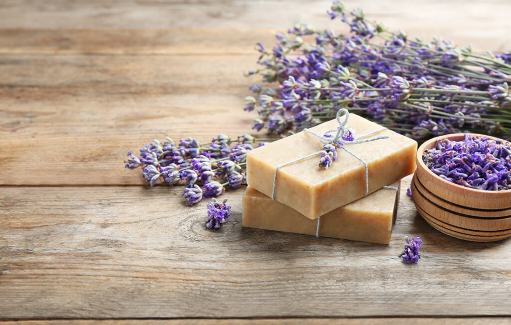 Handmade soap bars with lavender flowers on brown wooden table. 