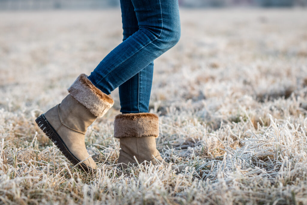 Woman wearing leather boots with fur at winter. Walking outdoors in hoarfrost. Female legs with skinny jeans. ; 